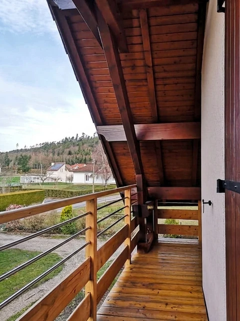 Balcon en bois de mélèze, vue extérieure sur jardin et colline boisée