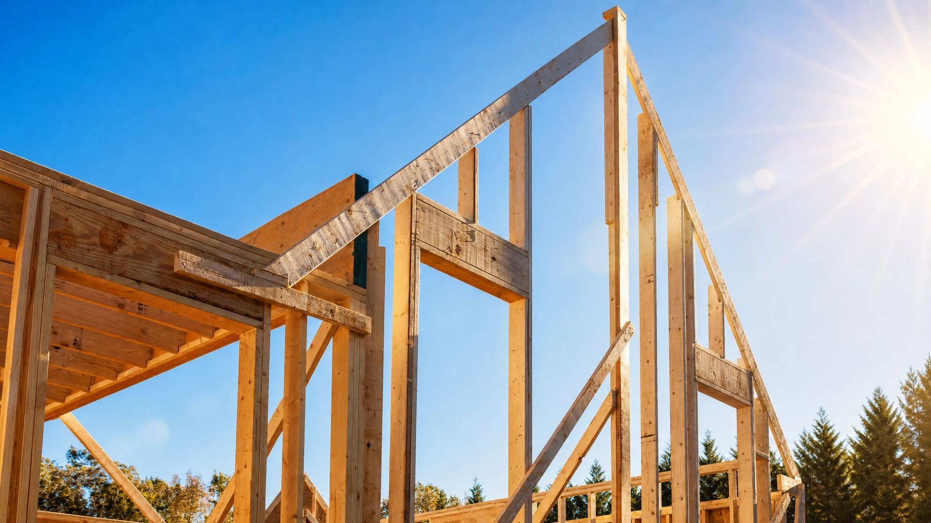 Construction d'une maison en bois en cours, structure à ossature bois avec bardage horizontal naturel, fondations en béton apparent